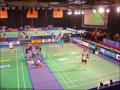 Imagem de jogadores de badminton, da quadra e dos árbitros.
<br><br>
Palavras-chave: esporte, badminton, raquete.